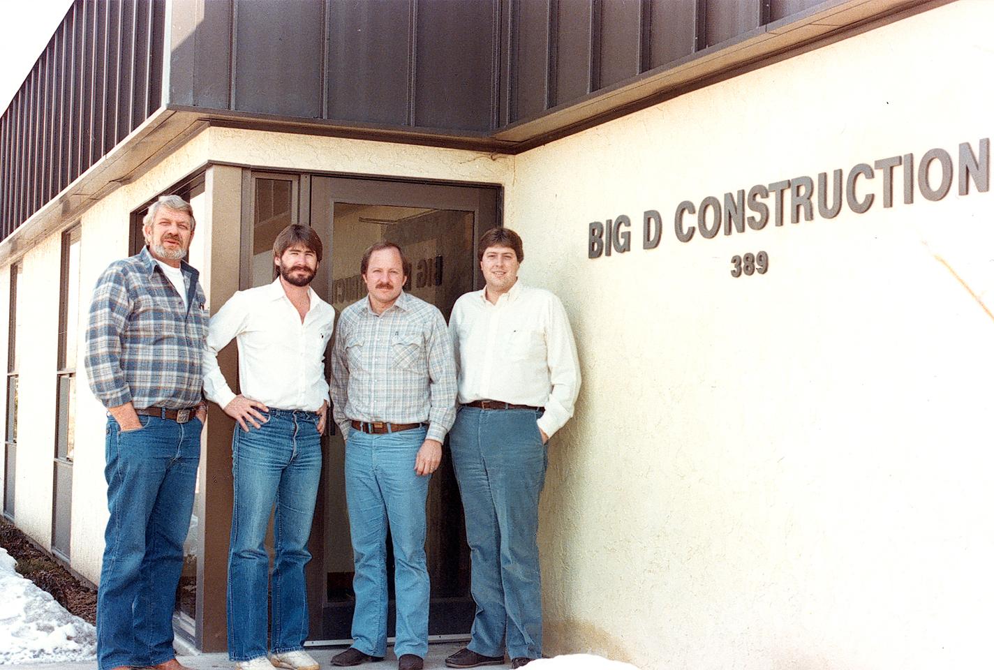 Four men, Dee Livingood and his young lions, standing in front of the Big-D office in 1976.
